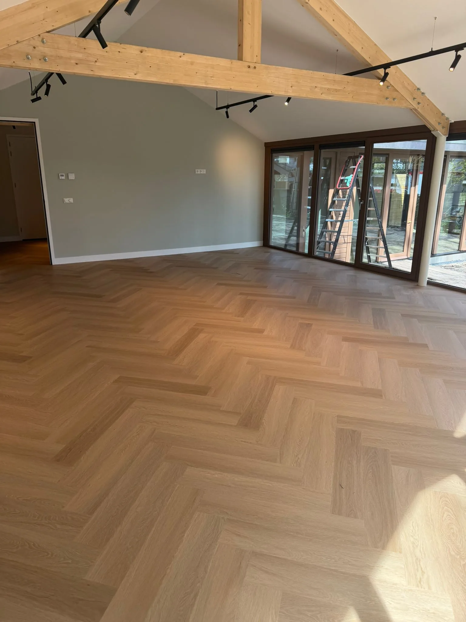 PVC visgraatvloer in een lichte woonkamer met openslaande tuindeuren