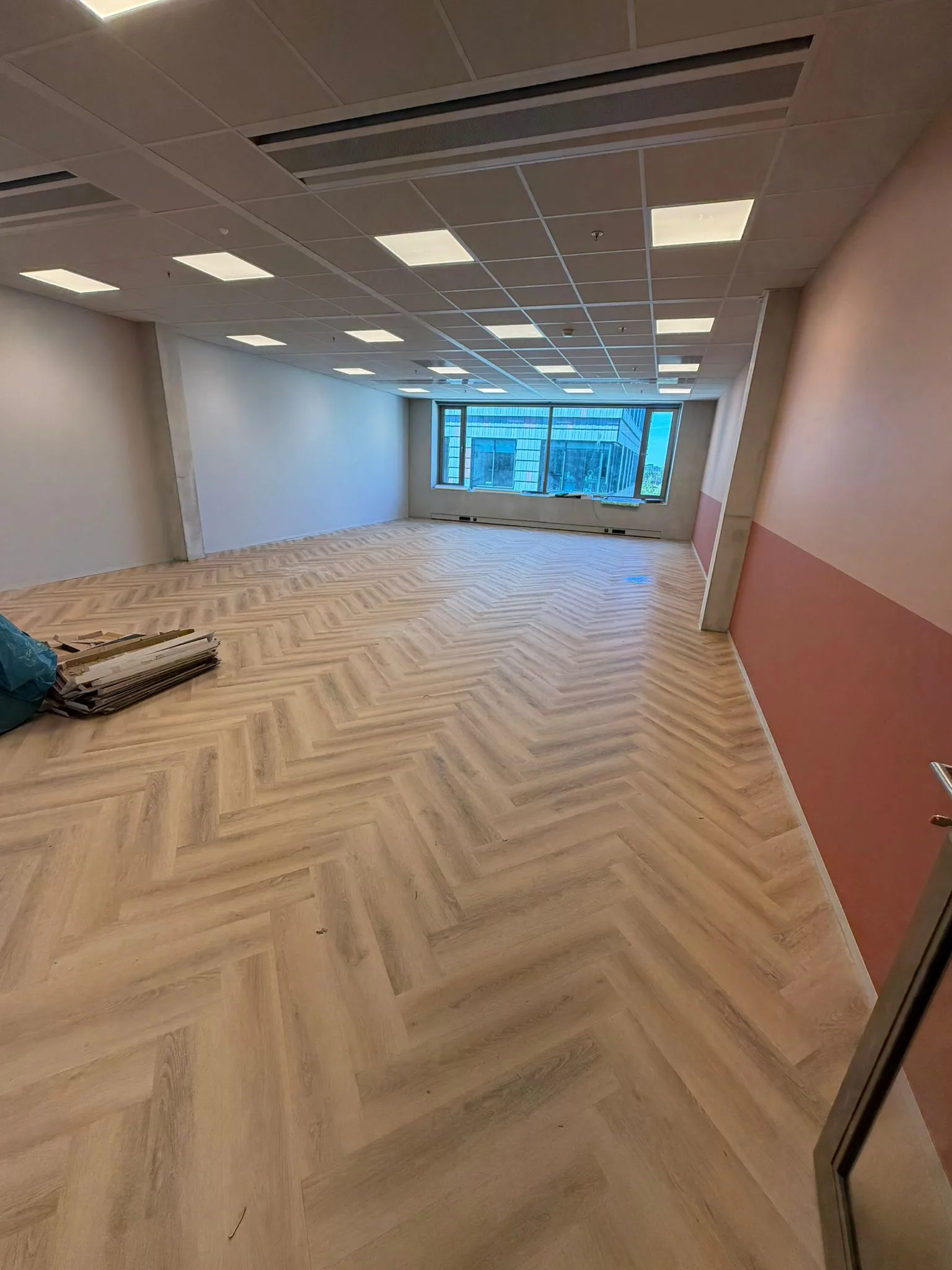 Visgraatvloer in een kantoorruimte met glaswand