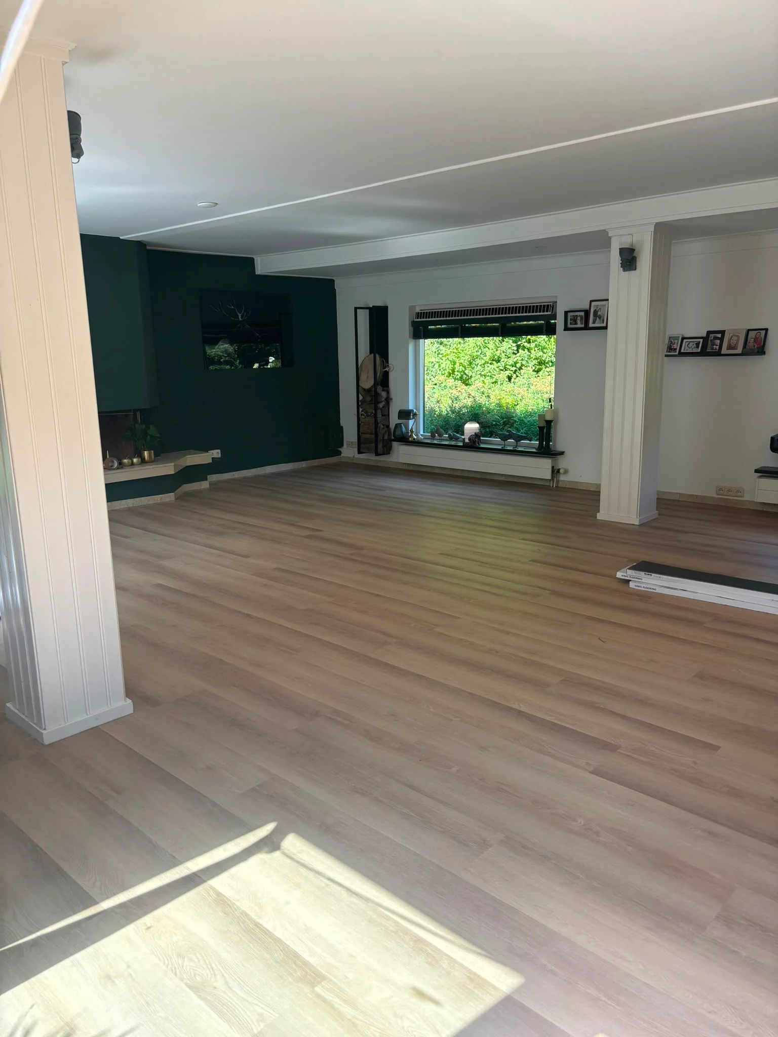 Rechte strook PVC vloer in een ruime woonkamer met donkergroene wand