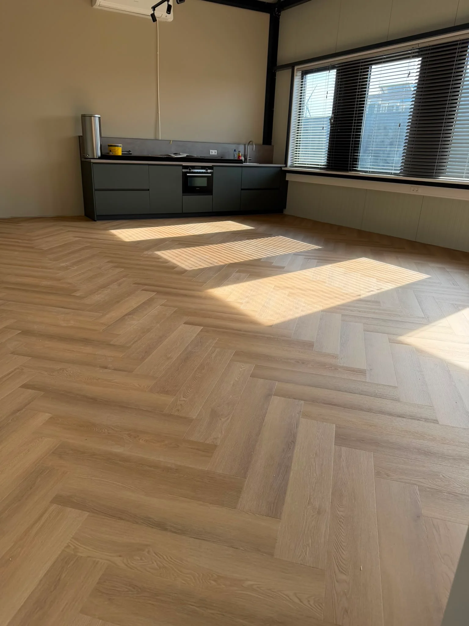 Visgraat PVC vloer doorlopend tot aan een donkere keuken