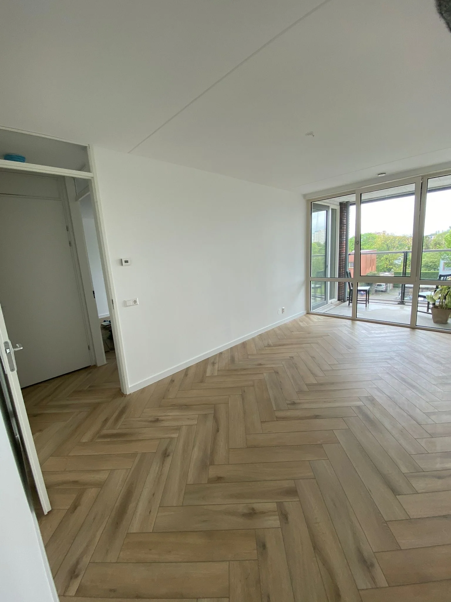 Visgraatvloer in een woonkamer met een brede raampartij naar de tuin