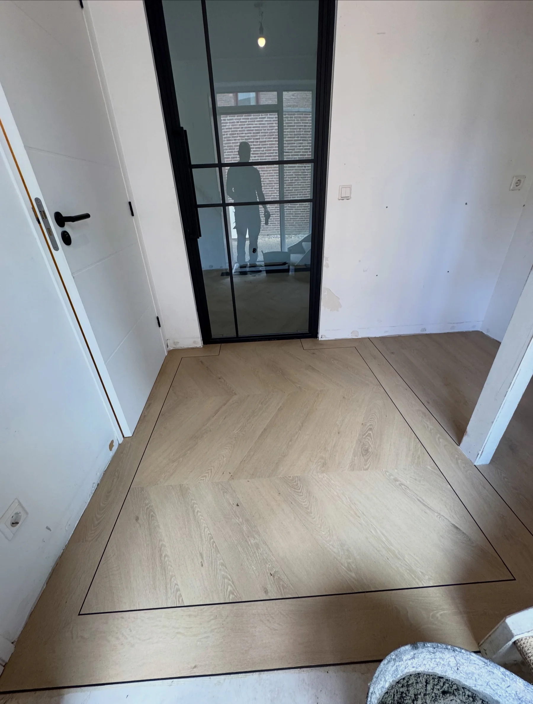 Walvisgraatvloer met bies, doorlopend tot aan een stalen binnendeur